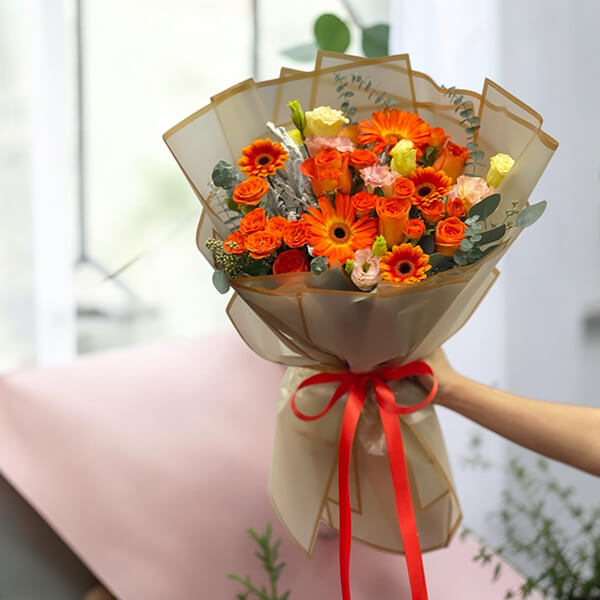 ช่อดอกไม้สดโทนสีส้มเหลืองสุดสดใส ผสมเยอบีร่า กุหลาบ และก้านยูคาลิปตัส สำหรับแสดงความยินดี Golden Hour Orange Gerbera and Rose Celebration Bouquet